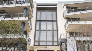 A modern building with a central entrance, stone facade, and multiple balconies.