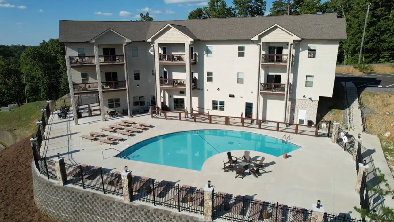 Un immeuble à plusieurs étages doté d’une piscine, d’un espace extérieur aménagé et de balcons.