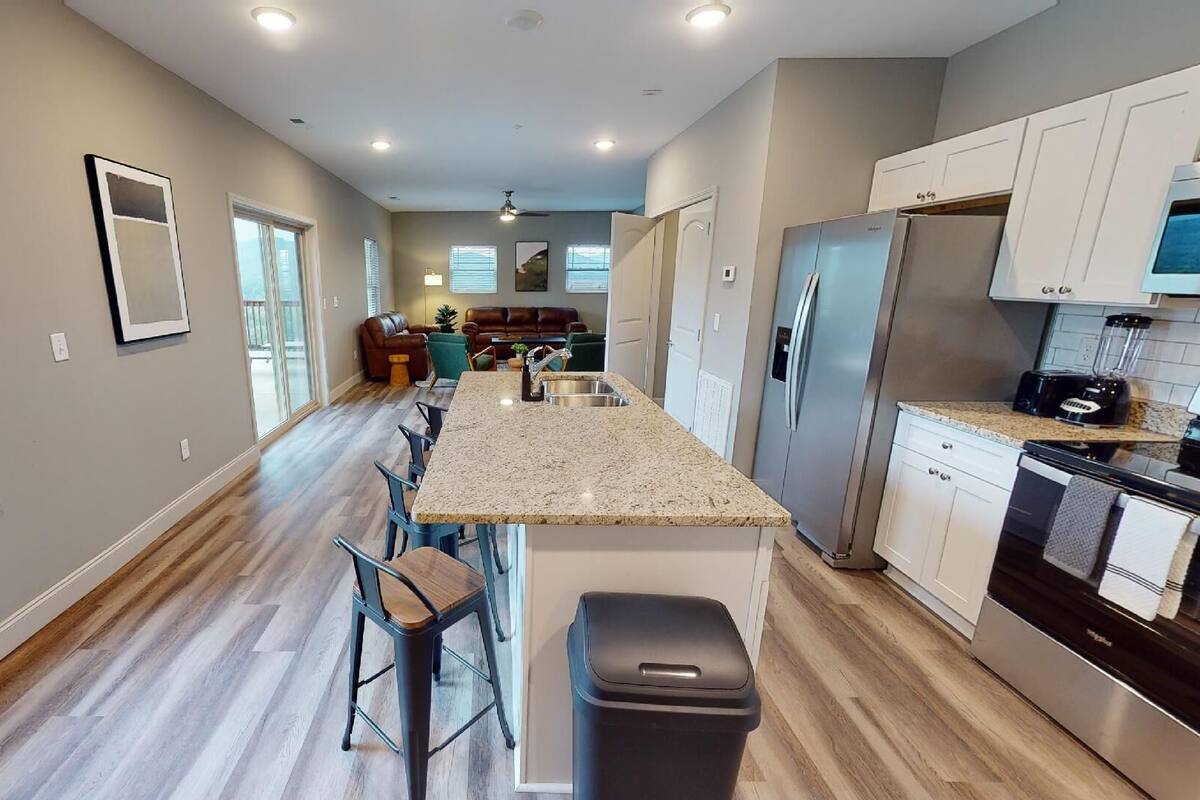 A modern kitchen with a central island, stainless steel appliances, and a view to the outside.