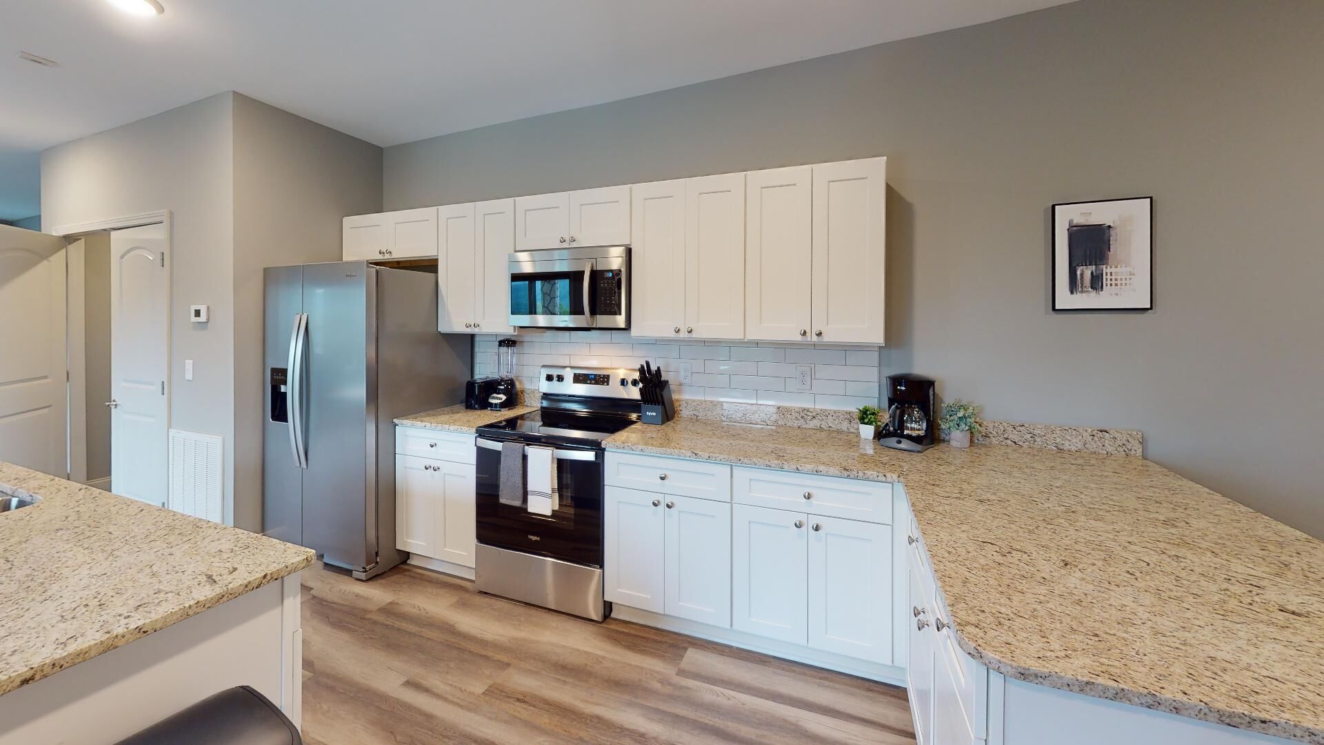A modern kitchen with white cabinets, stainless steel appliances, and granite countertops.