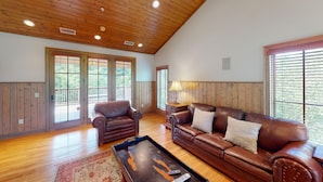 A spacious living room with wooden paneling, a leather sofa, a leather armchair, and a coffee table. - Viewpoint Condominiums (Pigeon Forge)