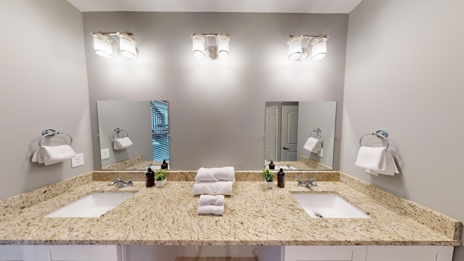 A modern bathroom with two sinks, a large mirror, and three wall-mounted lights.