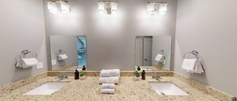 A modern bathroom with two sinks, a large mirror, and three wall-mounted lights.