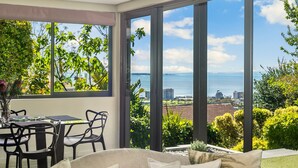 A modern room with large windows, a dining area, and a view of the sea.