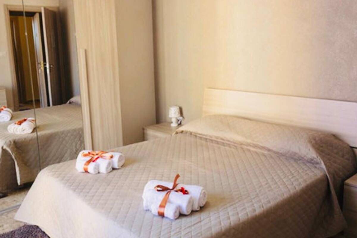 Une chambre d’hôtel avec deux lits, chacun agrémenté d’une serviette soigneusement pliée et d’une petite table à proximité.