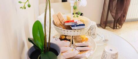 Ein Zimmer mit Esstisch, gedeckten Sandwiches und Brot, einer Topfpflanze und einer dekorativen Vase.