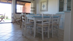 A dining area with a table and chairs, a window with curtains, and a cabinet with glass doors.