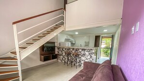 A modern interior with a staircase, a living area with a purple sofa, and a kitchen area with a geometric backsplash. - Bugio Flats (Angra dos Reis)