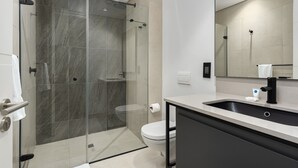 Un bagno moderno con box doccia in vetro, un water e un lavandino con rubinetto nero.