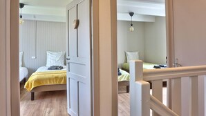 A room with a bed, a desk, and a chair. There is a window with curtains, and a door leading to another room. - Avaugour Vacation Rental: 5 bedrooms, 1 accessible for people with disabilities, in the Côtes d'Armor region of Brittany (Saint-Fiacre)