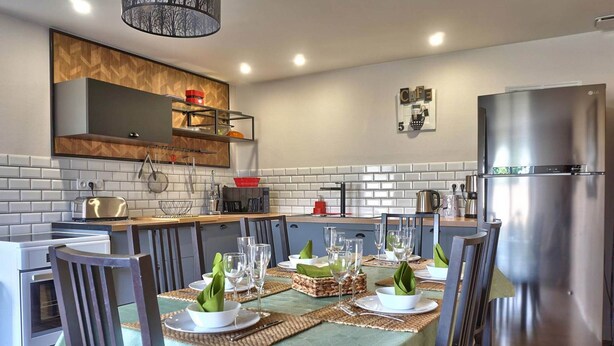 A modern kitchen with a dining area set for a meal. - Avaugour Vacation Rental: 5 bedrooms, 1 accessible for people with disabilities, in the Côtes d'Armor region of Brittany (Saint-Fiacre)
