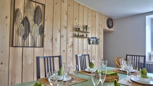 A dining area with a wooden wall, a clock, and a shelf with decorative items. - Avaugour Vacation Rental: 5 bedrooms, 1 accessible for people with disabilities, in the Côtes d'Armor region of Brittany (Saint-Fiacre)
