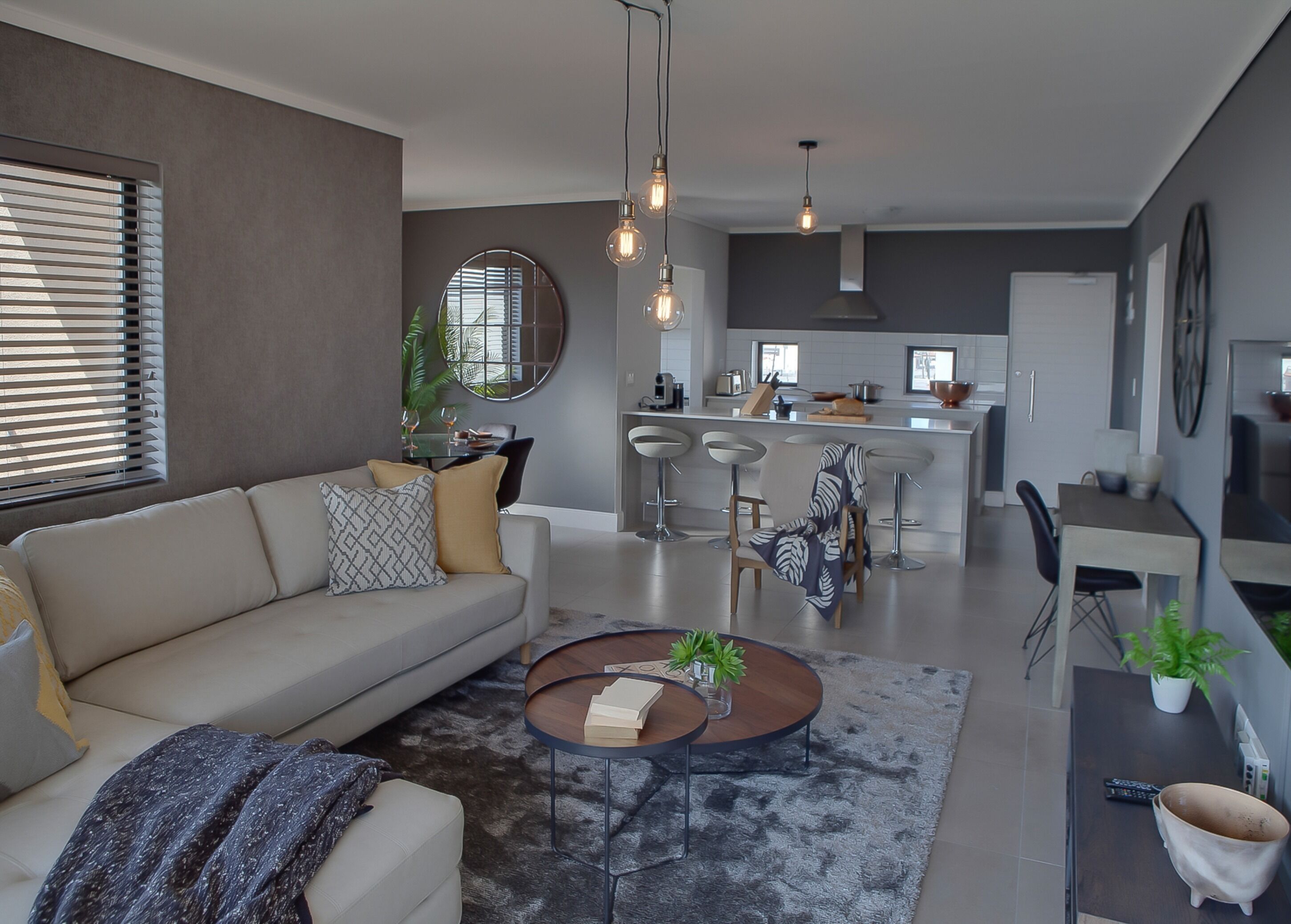 Un salon moderne comprenant un canapé, une table basse et un coin repas avec des chaises et une table.