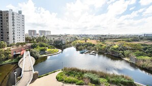 Vista a la orilla del río con un puente, edificios y vegetación.