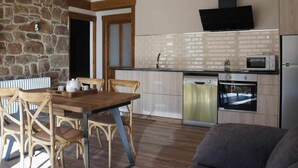 Una cocina moderna con pared de piedra, mesa de comedor de madera y sillas.