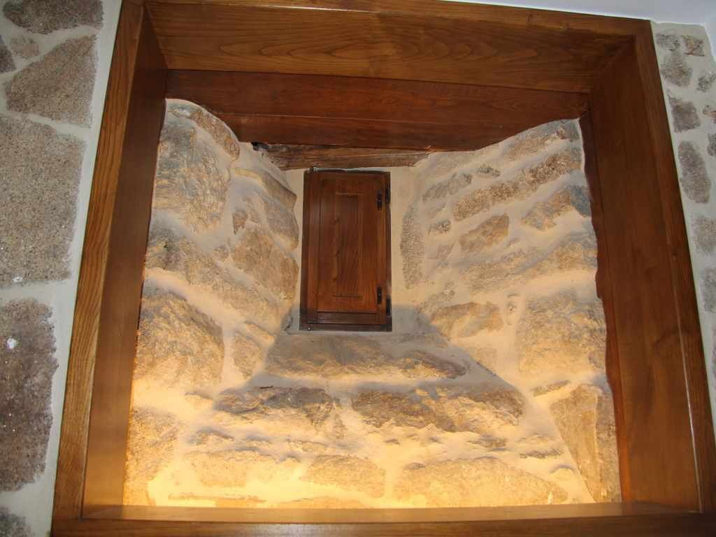 Eine Nische mit Steinwänden, einer Holztür und einem sichtbaren Deckenbalken.