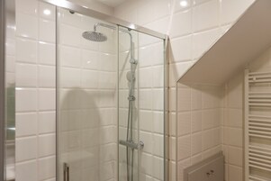 Ducha con cerramiento de vidrio, cabezal de ducha de mano, grifo empotrado y panel de control.