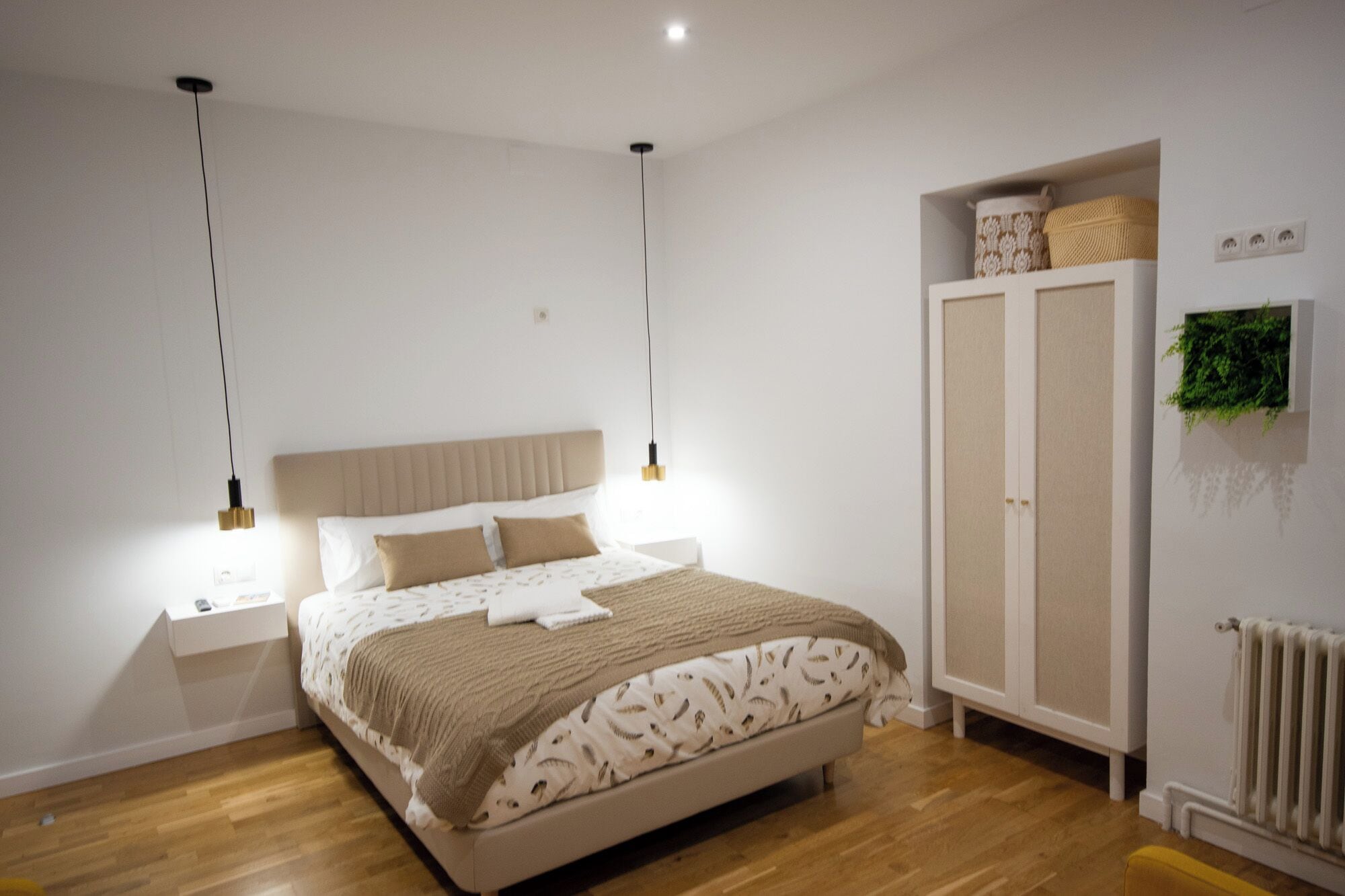 Une chambre à coucher comprenant un lit, des tables de chevet, une armoire et un radiateur.