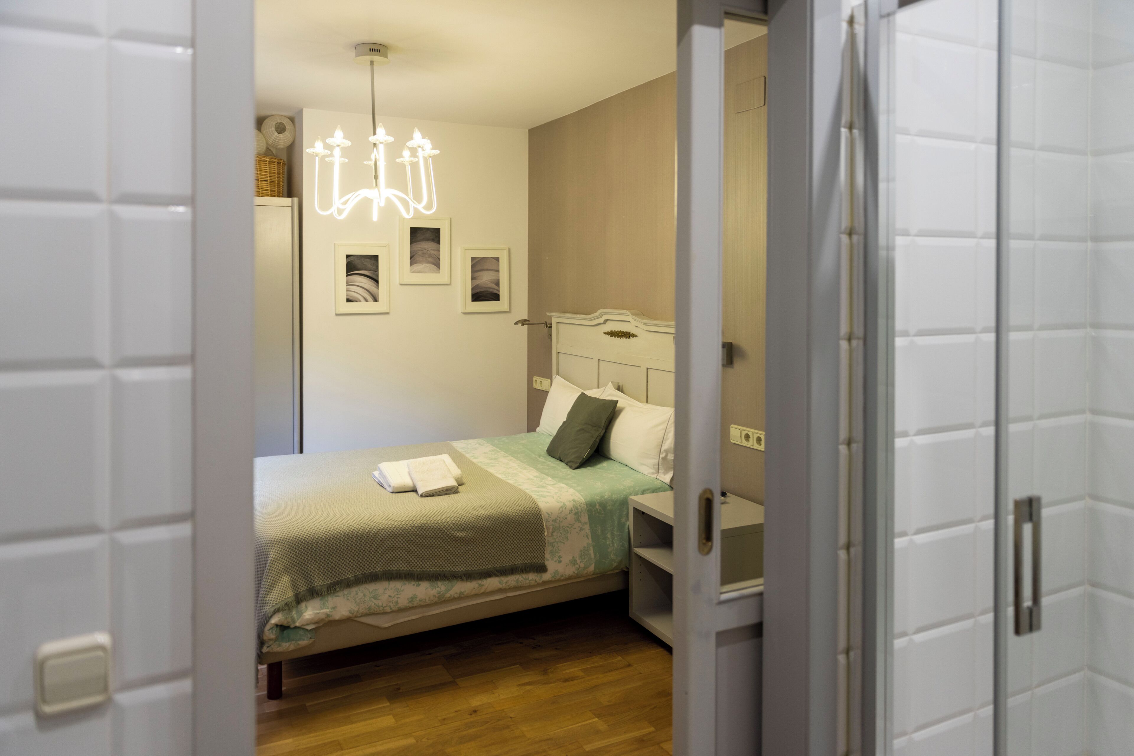 A bedroom with a bed, bedside table, and a wall-mounted light fixture.