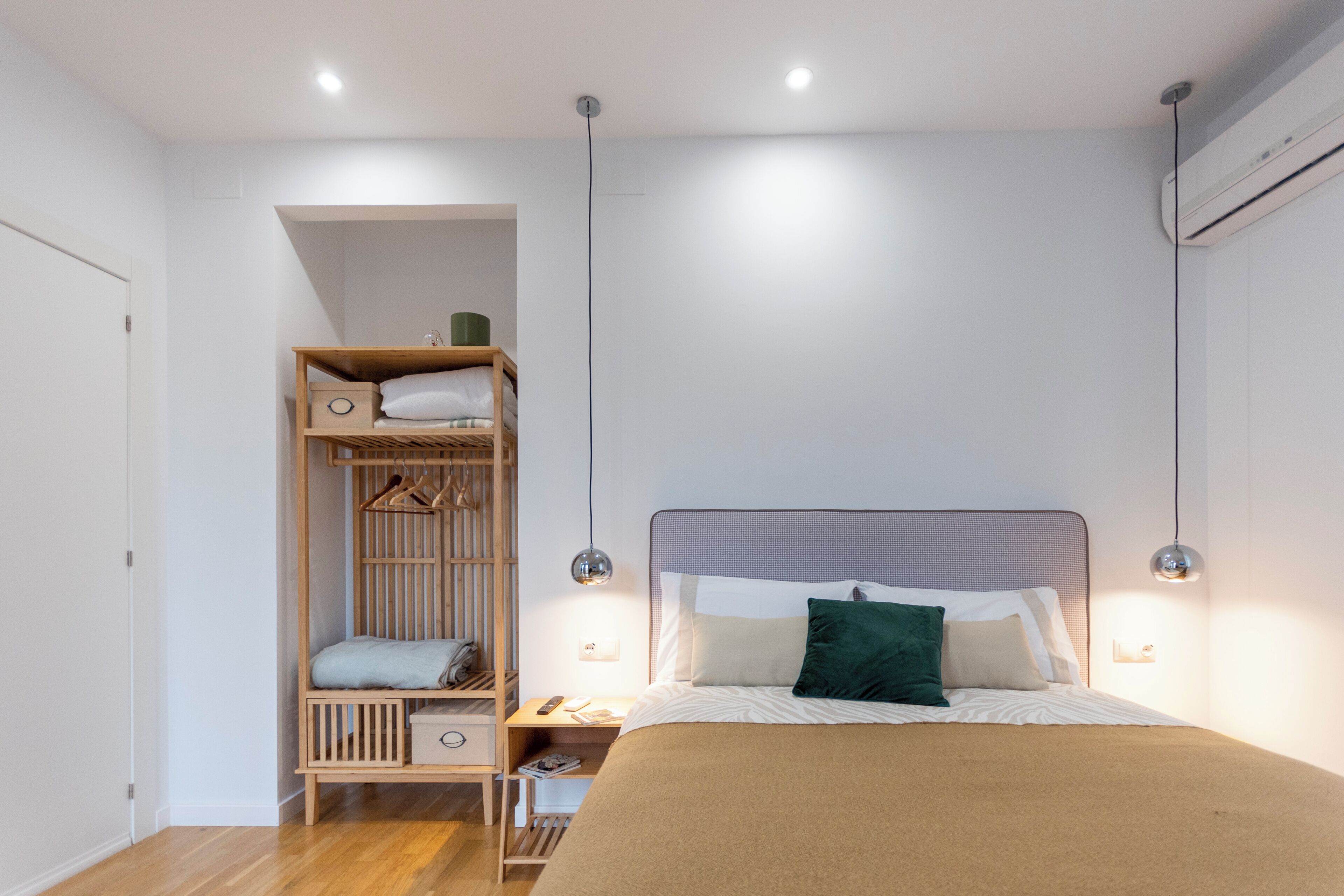 Une chambre avec un lit superposé, une table de chevet, une lampe et un climatiseur fixé au mur.