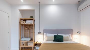 Une chambre avec un lit superposé, une table de chevet, une lampe et un climatiseur fixé au mur.