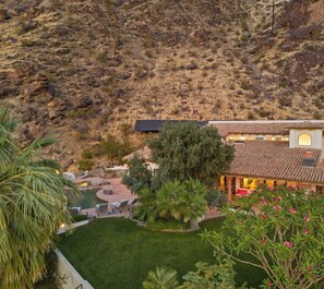 A house with a pool, surrounded by a well-maintained garden and a hilly landscape.