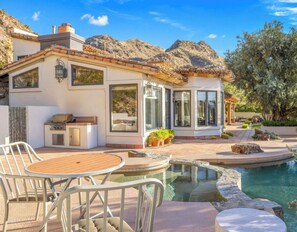 A modern house with a pool, outdoor seating, and a barbecue area.