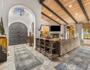 A spacious living area with a fireplace, a large sofa, and a TV mounted on the wall.