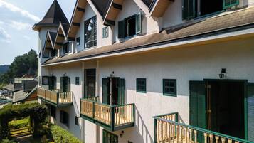A multi-story building with a symmetrical facade, green shutters, and a central balcony.