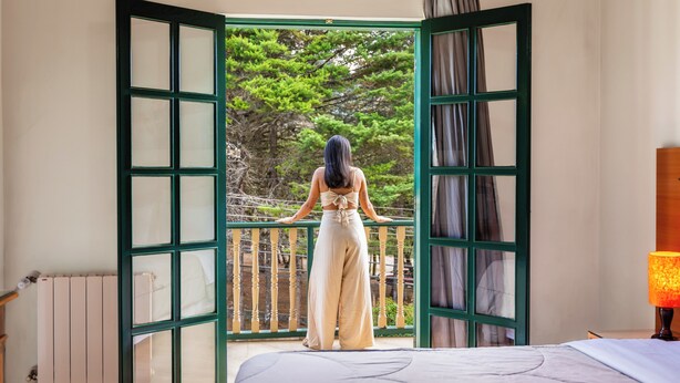 A room with a bed, a window with a view of trees, and a radiator. - Castelo Piazzale by Concavus (Campos do Jordão)