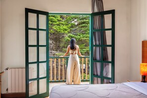 Une chambre avec un lit, une fenêtre donnant sur des arbres et un radiateur.
