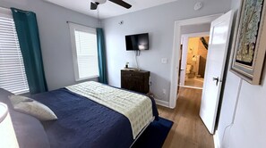 Een slaapkamer met een bed, een televisie, een dressoir en een deur naar een badkamer.