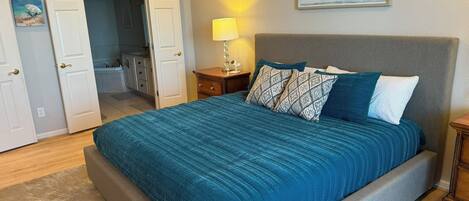 A bedroom with a bed, a nightstand, a lamp, and a painting on the wall.