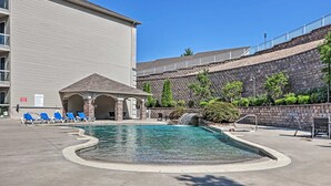 A swimming pool with lounge chairs, a covered seating area, and a stone retaining wall. - Lands End Condo 3Bd/3Bath End Unit with Amazing Main Channel View, Newly Updated (Osage Beach)