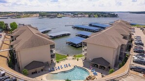 A hotel with a swimming pool, outdoor seating, and a view of a river with boats. - Lands End Condo 3Bd/3Bath End Unit with Amazing Main Channel View, Newly Updated (Osage Beach)