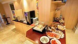 A buffet area with a refrigerator, coffee machine, and various food items. - Basic Hotel (Olerdola)