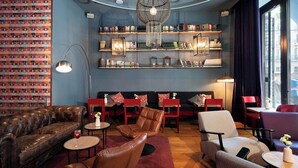 A cozy lounge area with leather sofas, a chandelier, and bookshelves filled with books and decorative items. - Basic Hotel (Olerdola)