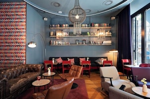 Cómoda sala de estar con sofás de cuero, una araña y estanterías llenas de libros y objetos decorativos.