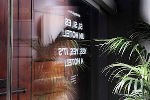 Una ventana de hotel con el reflejo de una persona y el texto que dice "UNHOTEL A YESTERDAY".