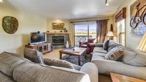 A living room with a fireplace, a television, and a sofa. - 2 Bedroom Lagoon Townhome with Awesome Lake Views!! (Frisco)