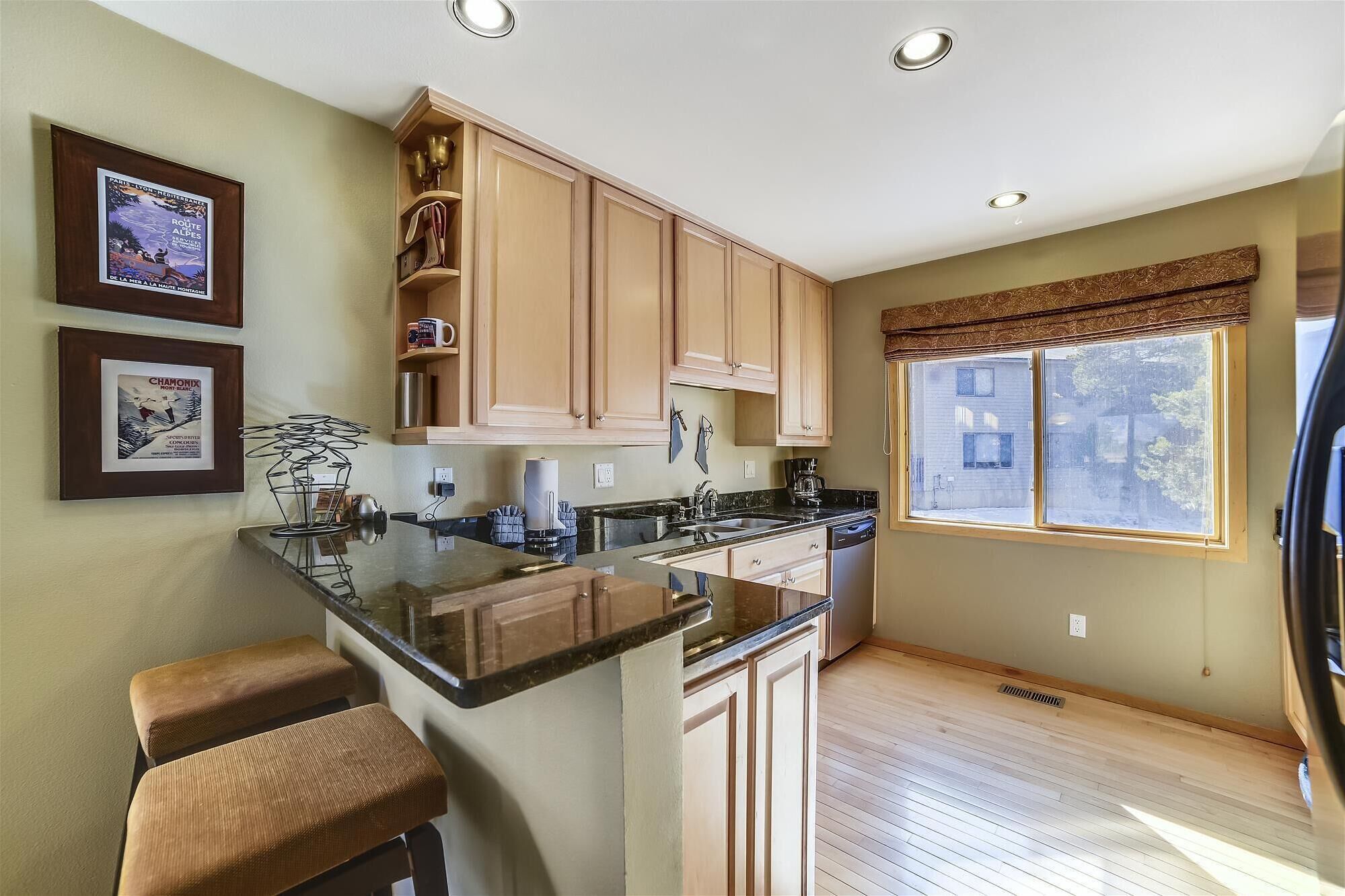 A modern kitchen with wooden cabinets, a granite countertop, and a large window.