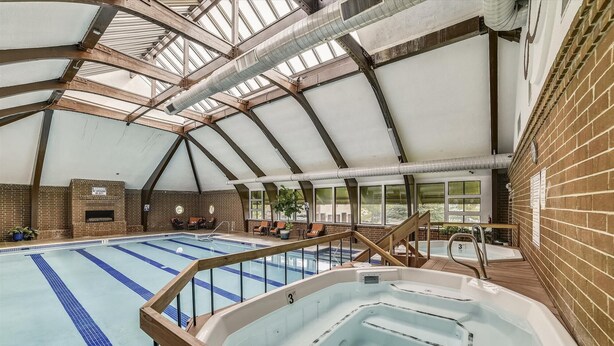 An indoor swimming pool with a hot tub, wooden deck, and brick walls. - 2 Bedroom Lagoon Townhome with Awesome Lake Views!! (Frisco)