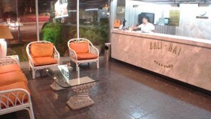 A reception area with a marble counter labeled "BALI-HAI" and a seating area with wicker chairs and a glass table. - Bali Hai (Acapulco)