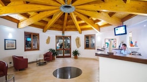 Eine Lobby mit Holzbalken, einem Empfangsbereich, roten Stühlen und einer großen, runden Bodeninstallation.