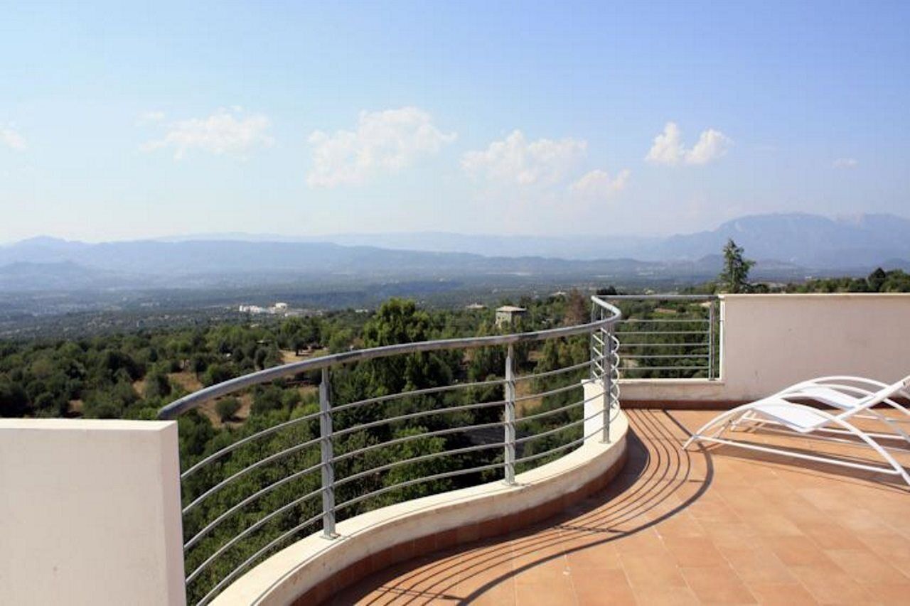 A rooftop terrace with a curved railing, offering a panoramic view of a mountainous landscape.