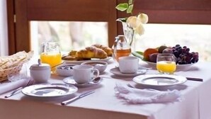 Ein Frühstückstisch mit Croissants, Obst, Saft und Kaffeetassen.