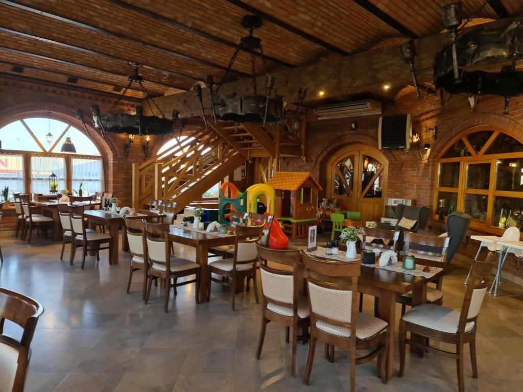 A restaurant with wooden tables and chairs, arched windows, and a rustic interior.