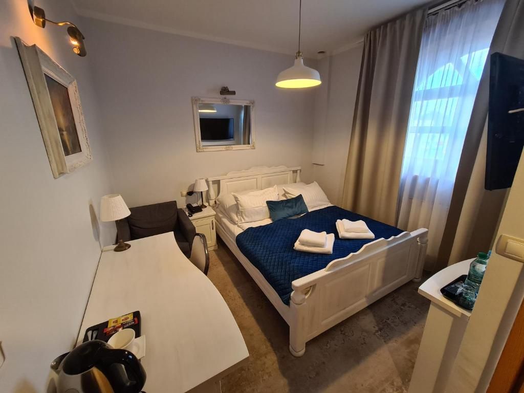 A hotel room with a bed, a desk, a chair, a TV, and a window with curtains.