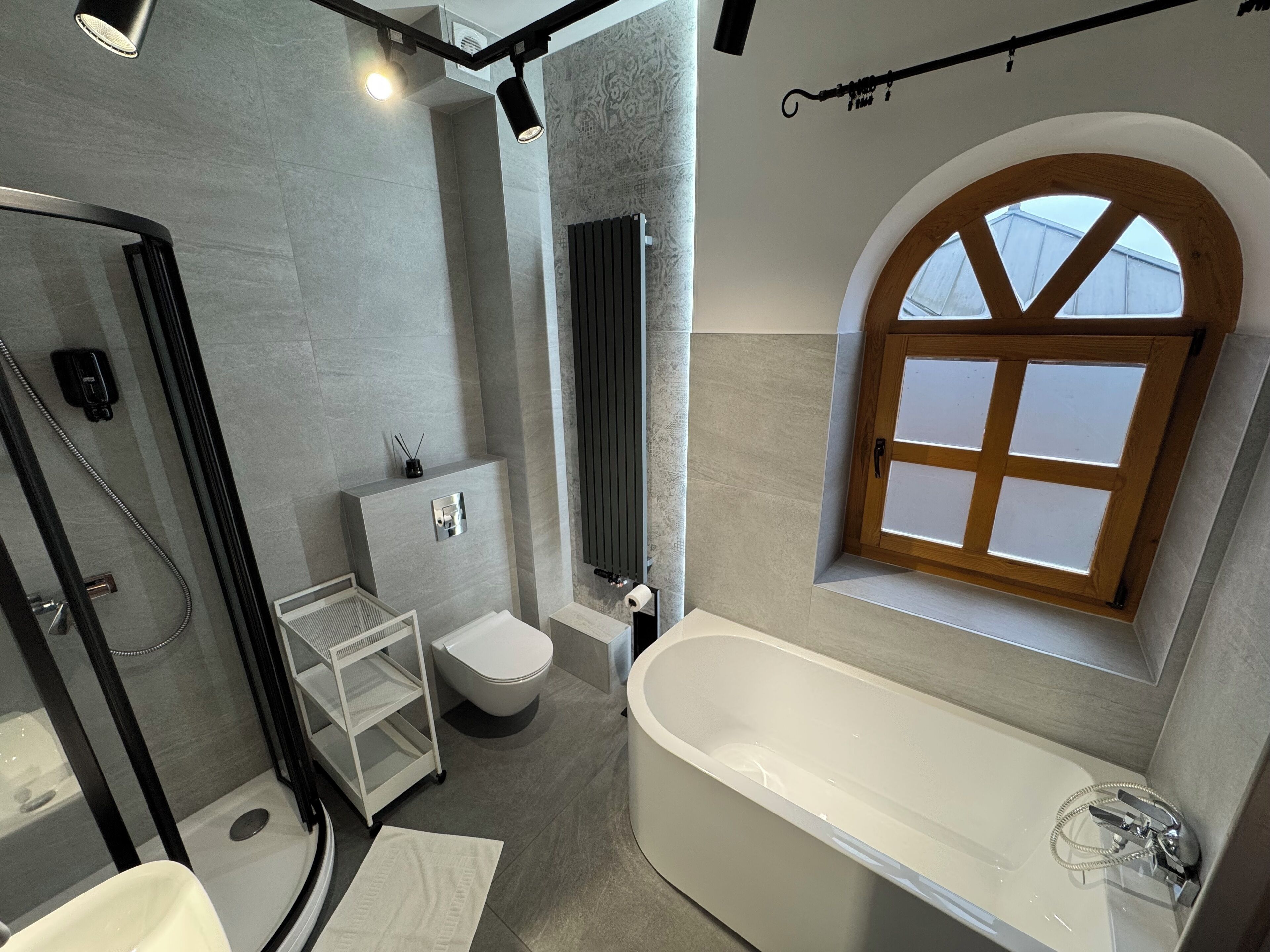 Un baño moderno con una bañera independiente, un inodoro, un box de ducha y un lavamanos con espejo.