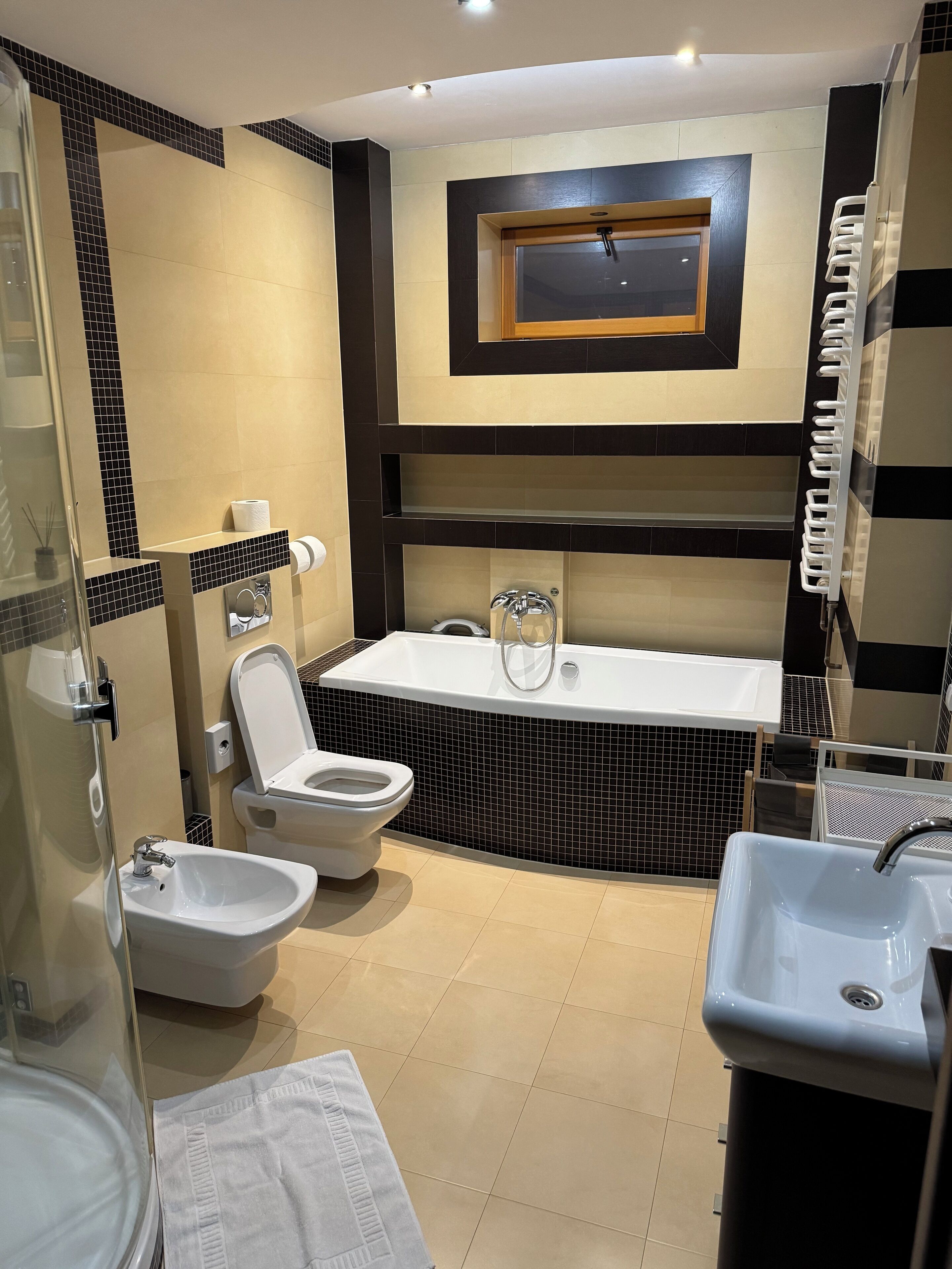 A modern bathroom with a bathtub, bidet, and two sinks.